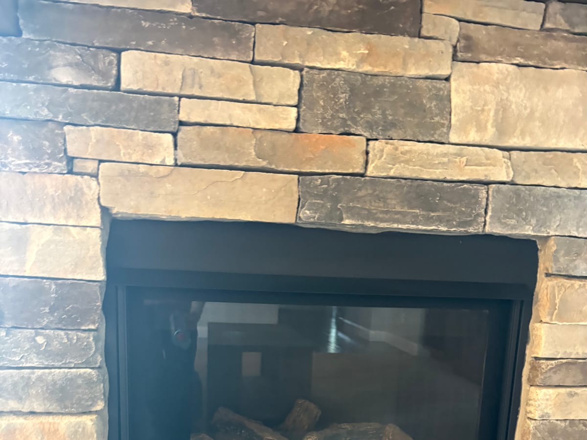 A finished gas fireplace in a stacked-stone surround serviced by XFire Solution